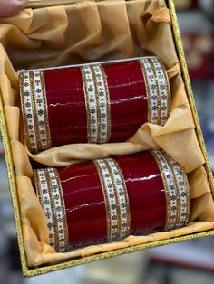 two rolls of red and gold ribbon wrapped around each other in a yellow gift box