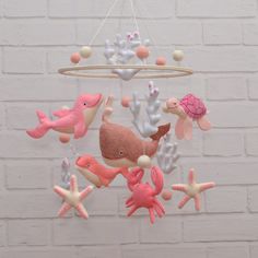 a mobile with sea animals and corals hanging from it's sides on a brick wall