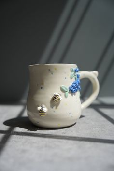 a white coffee cup with blue flowers on the outside and gold decorations on the inside