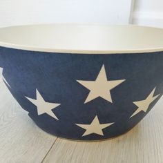 a blue bowl with white stars on it sitting on top of a wooden table next to a wall