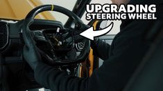 a man in black jacket driving a yellow truck with steering wheel and text overlaying the image