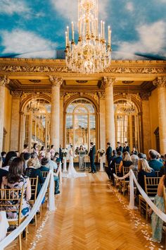 a wedding ceremony in an ornate building with chandelier