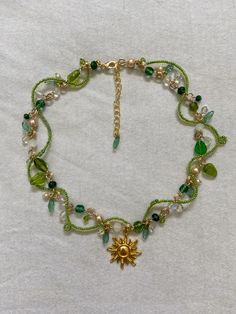 a green beaded bracelet with a gold sun charm and charms on the clasps