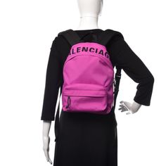 Balenciaga Nylon Wheel Logo Backpack Fuchsia. This stylish backpack is crafted of nylon in fuchsia. The bag features an embroidered black Balenciaga logo across the top, a front zipper pocket, a black canvas top handle, and adjustable padded black shoulder straps. The wrap-around silver zippers open the bag to a black nylon interior with zipper and patch pockets. This lovely backpack is spacious enough for all of your necessities, with the fashion forward appeal of Balenciaga!    Model: 565798 Nylon Bag With Embroidered Logo For Everyday Use, Everyday Nylon Bags With Embroidered Logo, Nylon Logo Backpack, Logo Nylon Backpack, School Nylon Bag With Logo, School Nylon Bags With Logo, Nylon Backpack With Logo For Everyday Use, Everyday Nylon Backpack With Logo, Designer Nylon School Backpack