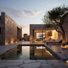 an outdoor swimming pool surrounded by stone walls and trees at dusk with the sun setting in the background