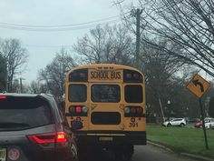 a yellow school bus driving down a street next to parked cars on the side of the road