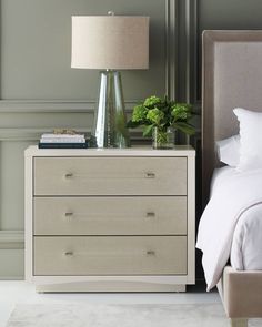 a bedroom with a bed, nightstand and lamp on the night stand in front of it