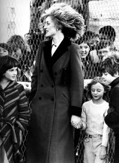 an old photo of a woman and two children holding hands while standing in front of a chain link fence