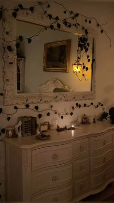 a white dresser sitting under a mirror next to a wall with lights on top of it