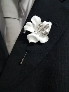 a white flower brooch sitting on top of a black suit