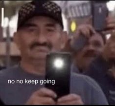 a man holding up a smart phone in front of a group of people on the street