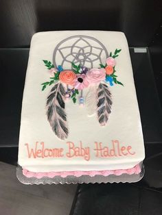 a baby shower cake with flowers and feathers on it that says welcome baby hadlee