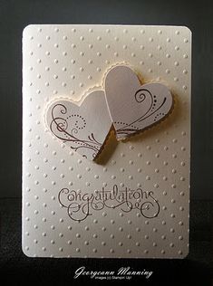 two paper hearts on a white card with congratulations written in the middle and writing underneath