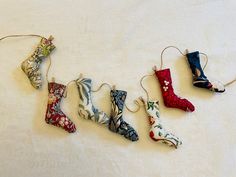 five different types of christmas stockings hanging from strings on a white sheet with snowflakes all over them