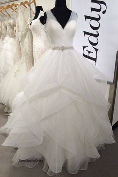 a white wedding dress on display in front of mannequins at a bridal shop