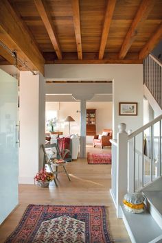 an open living room and dining area with wood ceilinging, white walls and wooden floors