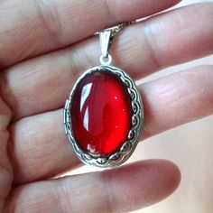 This beautiful locket is adored with a large 18x25 Ruby Red Green glass gem stone. Size: 24x30mm Chain Length: Per Option Qty: 1pc Red Cabochon Round Pendant Necklace, Red Cabochon Round Pendant Jewelry, Red Gemstone Oval Pendant Jewelry, Handmade Red Oval Cabochon Jewelry, Red Locket Necklace For Jewelry Making, Oval Cabochon Locket Necklace For Gift, Red Locket Jewelry For Valentine's Day, Red Locket Pendant Jewelry, Red Round Locket Jewelry