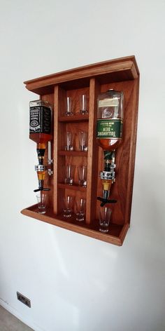 a wooden shelf filled with lots of glasses on top of a wall next to a white wall