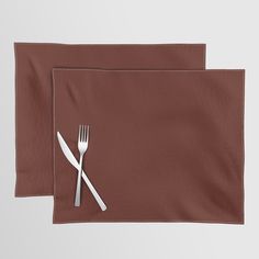 two place mats with forks and spoons on them, one has a brown napkin