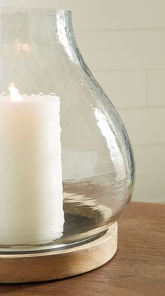 a lit candle in a glass vase on a wooden table