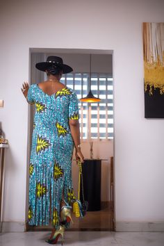 A woman posing in a blue and green African Print maxi dress with frills. Blue Ruffled Floor-length Maxi Dress, Blue Floor-length Ruffled Maxi Dress, Blue Floor-length Maxi Dress With Ruffles, Blue Bohemian Long Dress, Blue Printed Maxi Dress, Casual Ruffled Floor-length Maxi Dress, Casual Floor-length Ruffled Maxi Dress, Casual Floor-length Maxi Dress With Ruffles, Blue Long Dress With Ruffles