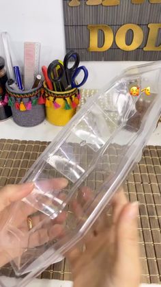 a person holding a clear plastic container with scissors and other items in front of them