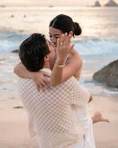 a man and woman are hugging on the beach