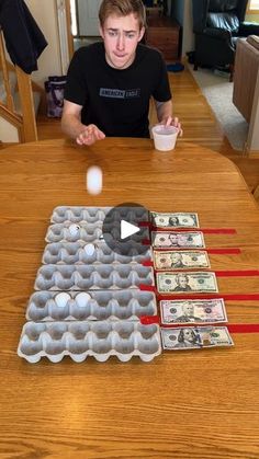 a young man sitting at a table with an egg carton and dollar bills in front of him