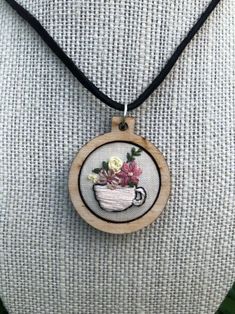 a necklace that has flowers in a cup on it