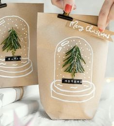 two bags with christmas trees on them are being held up by someone's hand