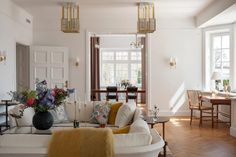 a living room filled with lots of furniture and flowers on top of the couches