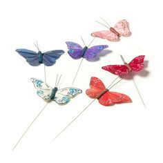 four different colored butterflies sitting on top of each other in the shape of hair pins