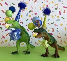 two toy dinosaurs with birthday hats and balloons