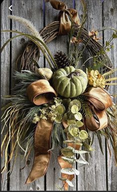 a wreath is hanging on the side of a wooden fence with green and brown decorations