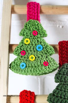 a crocheted christmas tree decoration hanging from a wooden ladder with colorful buttons on it