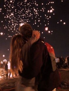 a man and woman embracing in front of fireworks