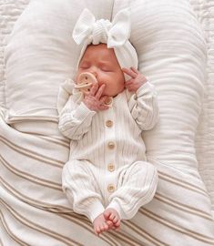 a baby laying on top of a bed with a pacifier in it's mouth