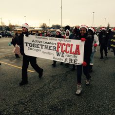 a group of people walking in a parking lot holding a sign