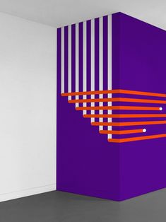 an abstract painting on the wall in a room with white walls and purple columns,