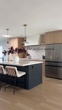 a large kitchen with an island in the middle and chairs at the end, along with a stainless steel refrigerator