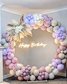 a birthday decoration with balloons and flowers in the shape of a circle on a wall