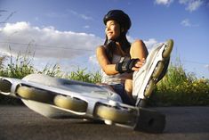 a woman sitting on the ground with her skateboard in front of her and an object behind her