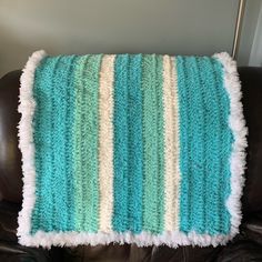 a blue and white blanket sitting on top of a leather chair