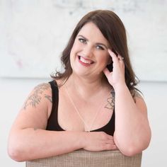 a woman sitting in a chair with her hand on her chin and smiling at the camera