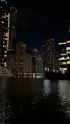 the city is lit up at night with lights reflecting off the water and buildings in the background