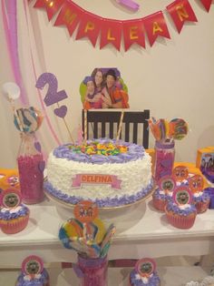 there is a birthday cake and cupcakes set up on the table with decorations