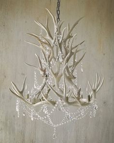 a chandelier made out of antlers hanging from a chain on a wall