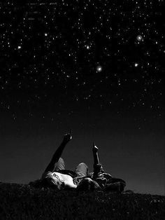 two people laying in the grass under stars