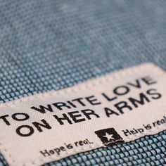 a label that says to write love on her arms is attached to a blue shirt