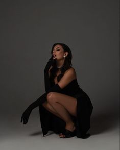 a woman sitting on the ground with her legs crossed and wearing black clothing, posing for a photo